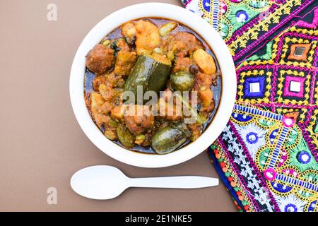 Undhyu oder Oondhyu ein gujarati Delikatessengericht serviert in handi Schüssel mit Hintergrund von gujarati kutchi bharatkam handgefertigten Stickdesign. Mehrfarbige tr Stockfoto