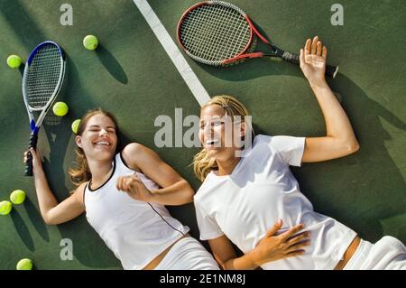 Erschöpfte Frauen liegen nach dem Spielen auf dem Tennisplatz Stockfoto