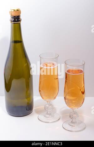 Grüne Flasche mit Champagner innen und zwei Gläser mit Champagner 'rosé' auf weißem Hintergrund. Stockfoto