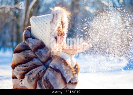 Junges Mädchen bläst Schnee aus ihren Handflächen Stockfoto