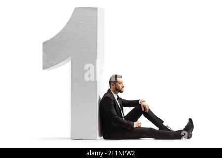 Trauriger Geschäftsmann, der auf dem Boden saß und sich an die Nummer lehnte Eine isoliert auf weißem Hintergrund Stockfoto