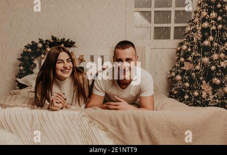 Paar Mann und Frau liegen auf Bett Schlafzimmer in der Nähe von weihnachten tree.decorated Haus für New Year.Christmas Morning. Wohnung Interieur. Valentinstag Promi Stockfoto