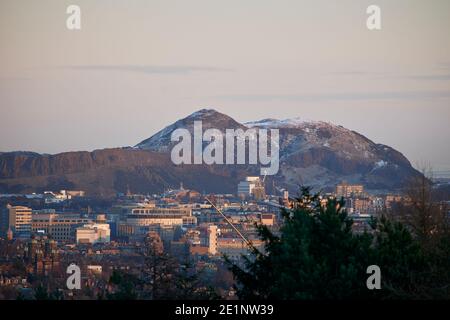 Ein Winterblick mit Schnee, Blick von Corstorphine Hill in Richtung Edinbugh 's Arthurs Sitz, mit Wanderern, Wanderer auf dem Hügel. Stockfoto