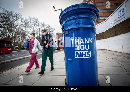 Krankenschwestern mit Gesichtsmasken kommen an einem blau gestrichenen Briefkasten vorbei und tragen die Botschaft „Thank You NHS“ vor dem St. Thomas' Hospital in London, Großbritannien Stockfoto