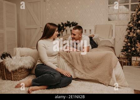 Paar Mann und Frau liegen auf Bett Schlafzimmer in der Nähe von weihnachten tree.decorated Haus für New Year.Christmas Morning. Wohnung Interieur. Valentinstag Promi Stockfoto