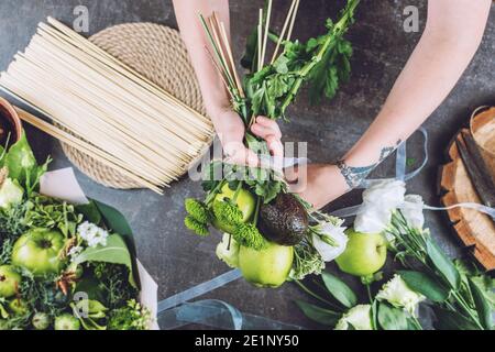 Hobbys und Aktivitäten, Kunst und Kunsthandwerk während Coronavirus. Floristin Frau machen Obst essbare Bouquet. Natürlichkeit, Blumenarrange, Floristen-Tricks Stockfoto