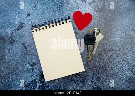 Notizblock, rotes Herz und valentinstag-Geschenkschlüssel auf grauem Hintergrund Stockfoto