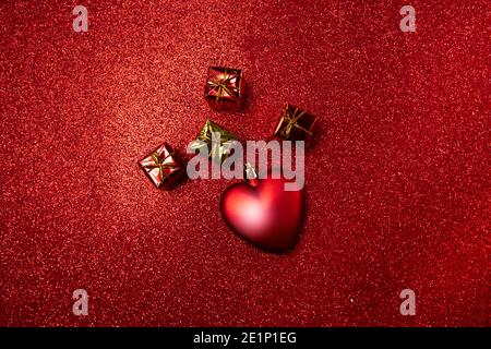 Herz und kleine rote Geschenkschachteln auf rotem Hintergrund. valentinstag-Konzept Stockfoto