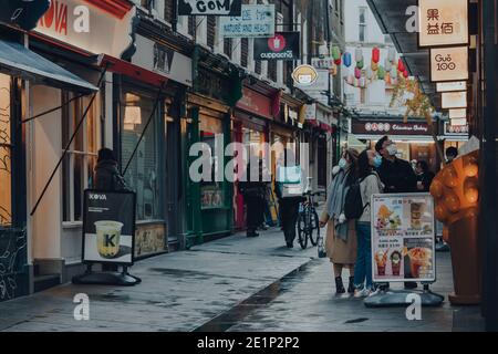London, Großbritannien - 19. November 2020: Menschen mit Gesichtsmasken in Chinatown in London. Chinatown ist die Heimat einer großen ostasiatischen Gemeinde und berühmt Stockfoto