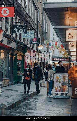 London, Großbritannien - 19. November 2020: Menschen mit Gesichtsmasken in Chinatown in London. Chinatown ist die Heimat einer großen ostasiatischen Gemeinde und berühmt Stockfoto