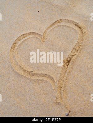 Romantik im Sand geschrieben, eine Liebesbotschaft am Strand durch ein Liebesherz im Sand Stockfoto