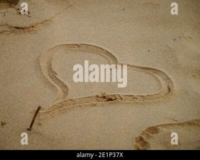 Romantik im Sand geschrieben, eine Liebesbotschaft am Strand durch ein Liebesherz im Sand Stockfoto