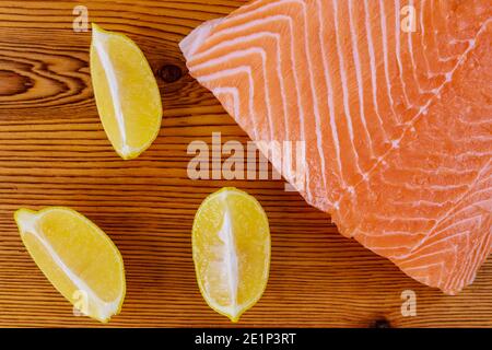 Frisches Lachsrohfilet mit Zitrone auf Holzbrett Stockfoto