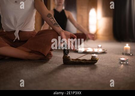 Anonyme Frau, die Gyan mudra gestikuliert und in Lotus-Pose meditiert Nahe Weihrauch Stockfoto