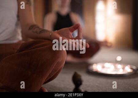 Anonyme weibliche Gestik Gyan Mudra und Meditation während der Sitzung in Dunkles Zimmer Stockfoto