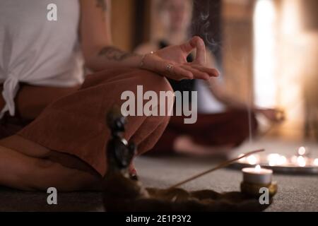 Eine Frau, die Gyan mudra gestikuliert und in der Nähe von Räucherwerk meditiert Im Studio Stockfoto