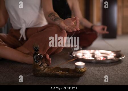 Cropped Frau gestikulierenden Gyan Mudra während der Meditation in der Nähe von Weihrauch und Kerzen Stockfoto