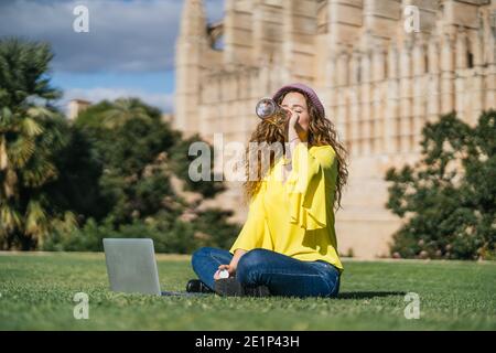 Junge Frau Trinkwasser auf dem Rasen Stockfoto