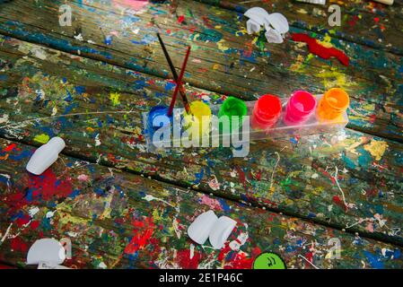 Overhead-Ansicht der Pinsel in Farbtöpfen auf unordentlichen Tisch Stockfoto