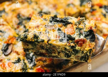 Entfernen einer Portion Chorizo Eierauflauf aus einer Pfanne Stockfoto