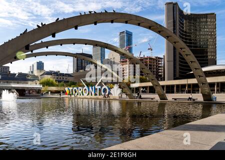 Bögen und neues Toronto-Schild am Nathan Phillips Square mit der Skyline der Stadt im Hintergrund. Stockfoto