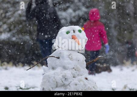 Madrid, Spanien - 08. Januar 2021: Kinder, die mit Schnee spielen und Schneemänner machen, im Buen Retiro Park in Madrid, mitten in einem verschneiten Tag, fällig Stockfoto