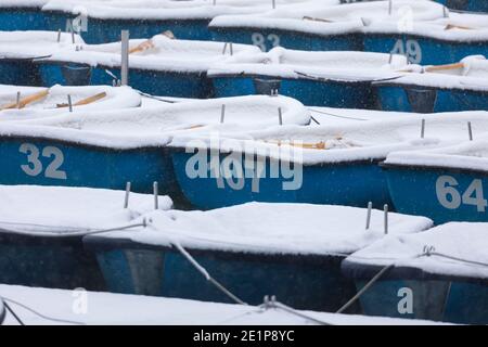 Madrid, Spanien - 08. Januar 2021: Boote mit Schnee bedeckt und vertäut in der Estanque Grande del Retiro, Madrid, in der Mitte eines verschneiten Tages, aufgrund einer Stockfoto