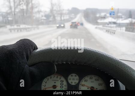 Die Hand des Fahrers hinter dem Steuer eines Auto in einem warmen Handschuh Stockfoto