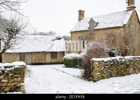 Cotswold Steinhütte und Scheune im Dezember Schnee. Taynton, Cotswolds, Oxfordshire, England Stockfoto