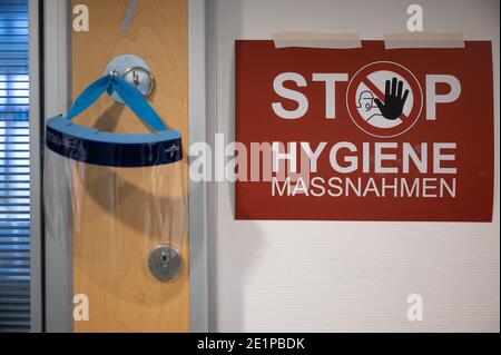 Ludwigsburg, Deutschland. Januar 2021. Ein Gesichtsschutz hängt auf einer Intensivstation des RKH Klinikums Ludwigsburg neben einem Schild mit der Aufschrift "Hygiene-Maßnahmen". In Baden-Württemberg wird die Belegung von Intensivstationen über ein Cluster-Konzept gesteuert. Intensivpatienten können zwischen den Kliniken der sechs Servicebereiche verlegt werden, um eine bessere Verteilung zwischen den Krankenhäusern zu erreichen. Quelle: Sebastian Gollnow/dpa/Alamy Live News Stockfoto