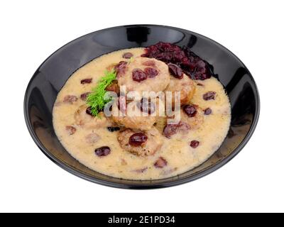 Fleischbällchen im schwedischen Stil in cremiger Sauce mit Preiselbeeren und Cranberry-Sauce in einer schwarzen Schüssel isoliert auf einem weißen Hintergrund Stockfoto