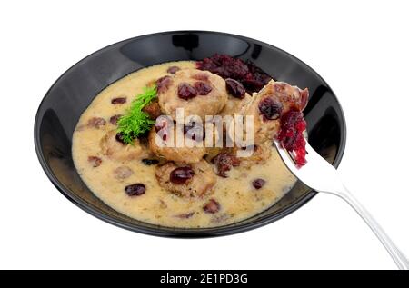 Fleischbällchen im schwedischen Stil in cremiger Sauce mit Preiselbeeren und Cranberry-Sauce in einer schwarzen Schüssel isoliert auf einem weißen Hintergrund Stockfoto