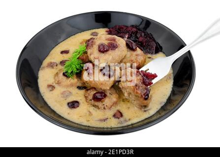 Fleischbällchen im schwedischen Stil in cremiger Sauce mit Preiselbeeren und Cranberry-Sauce in einer schwarzen Schüssel isoliert auf einem weißen Hintergrund Stockfoto