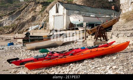 LULWORTH, DORSET, UK - 17. MÄRZ 2009: Seekajaks am Strand von Lulworth Cove mit Booten und Schuppen im Hintergrund Stockfoto