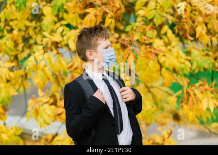 Schuljunge geht aus der Schule tragen Schutzmaske in der Stadt Stockfoto