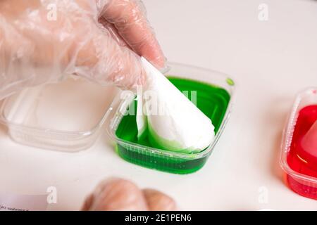 Chemie aus- und Weiterbildungskonzept. Nahaufnahme einer Frau, die einen Kegel in eine Lösung in einem Verbindungsstück eintaucht, um eine chemische Reaktion zu induzieren und zu wachsen Stockfoto