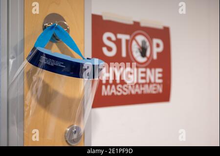 Ludwigsburg, Deutschland. Januar 2021. Ein Gesichtsschutz hängt auf einer Intensivstation des RKH Klinikums Ludwigsburg neben einem Schild mit der Aufschrift "Hygiene-Maßnahmen". In Baden-Württemberg wird die Belegung von Intensivstationen über ein Cluster-Konzept gesteuert. Intensivpatienten können zwischen den Kliniken der sechs Servicebereiche verlegt werden, um eine bessere Verteilung zwischen den Krankenhäusern zu erreichen. Quelle: Sebastian Gollnow/dpa/Alamy Live News Stockfoto