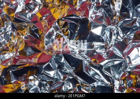Abstrakter Hintergrund mit zerknittert Folie Textur, Silber, rot und gelb Farben. Stockfoto