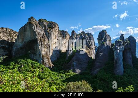 Mittags Blick auf Meteora Felsen, sedimentäre Klippen zwischen hellen Frühlingsgrün des Tales. Klarer blauer Himmel, Sonnenschein. Griechenland, UNESCO-Weltkulturerbe Stockfoto