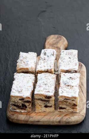 Weihnachtsstollen Scheiben mit Preiselbeere auf schwarzem Stein Hintergrund Stockfoto