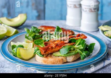 Sardinen in Tomatensauce mit Avocado und Lammsalat Toast Stockfoto