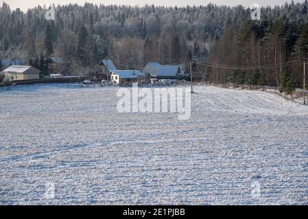 Ein schneebedecktes Dorf am Rande eines weiten Feldes. Stockfoto