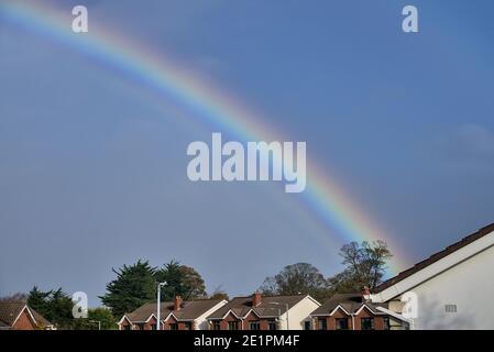 Blick auf Hausdächer im Süden Dublins mit einem wunderschönen Regenbogen, der den Baum berührt, der während der Coronavirus-Sperre aus einem Fenster in Dublin, Irland, gefangen wurde Stockfoto