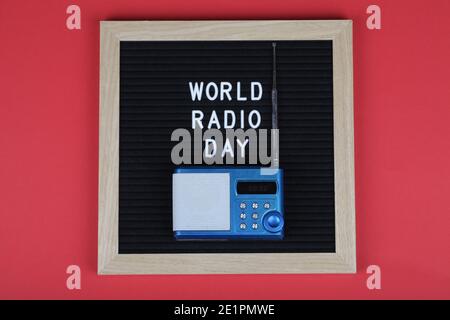 Schwarzes Briefbrett mit Text Welt Radio Tag mit blauem Radio auf rotem Hintergrund. Draufsicht. Flach legen minimalen Hintergrund. Stockfoto
