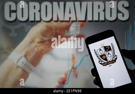 Das Port Vale Football Club Logo auf einem Mobiltelefon mit Coronavirus-Illustration auf einem Monitor in Der Hintergrund Stockfoto