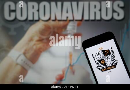 Das Port Vale Football Club Logo auf einem Mobiltelefon mit Coronavirus-Illustration auf einem Monitor in Der Hintergrund Stockfoto