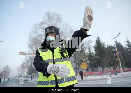 Dahinggan, Chinas Provinz Heilongjiang. Januar 2021. Verkehrspolizist Sun Chen leitet den Verkehr an einer Kreuzung im Bezirk Huzhong in Dahinggan, nordöstlich der Provinz Heilongjiang, 8. Januar 2021. Sun Chen ist seit 35 Jahren Verkehrspolizist. Im Bezirk Huzhong, genannt "die kälteste Stadt Chinas", klebte Sun an seinem Posten, um die Verkehrsordnung aufrechtzuerhalten. Trotz des extrem kalten Wetters mit der niedrigsten Temperatur von etwa minus 40 Grad Celsius nahm er früh am Morgen seine Schicht auf. Quelle: Wang Jianwei/Xinhua/Alamy Live News Stockfoto