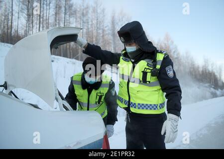 Dahinggan, Chinas Provinz Heilongjiang. Januar 2021. Der Verkehrspolizist Sun Chen (R) und sein Kollege bereiten Werkzeuge vor, um eine Straße im Bezirk Huzhong in Dahinggan, nordöstlich der Provinz Heilongjiang, abzulegen, 8. Januar 2021. Sun Chen ist seit 35 Jahren Verkehrspolizist. Im Bezirk Huzhong, genannt "die kälteste Stadt Chinas", klebte Sun an seinem Posten, um die Verkehrsordnung aufrechtzuerhalten. Trotz des extrem kalten Wetters mit der niedrigsten Temperatur von etwa minus 40 Grad Celsius nahm er früh am Morgen seine Schicht auf. Quelle: Wang Jianwei/Xinhua/Alamy Live News Stockfoto