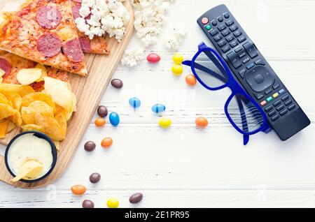 Fast Food und ungesunde Snacks, 3D-Brille und Fernbedienung auf weißem Hintergrund. Ein Stillleben-Thema, das auf der Erfahrung von 3D-Kinounterhaltung basiert Stockfoto
