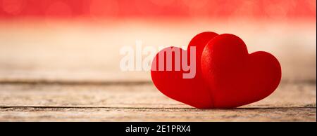 Zwei rote Herzen auf Holztisch und roter Hintergrund Stockfoto